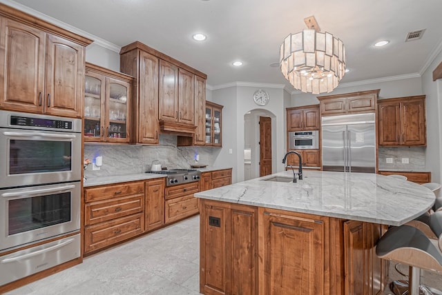 kitchen with arched walkways, a sink, visible vents, appliances with stainless steel finishes, and a warming drawer