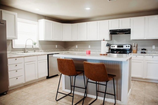 kitchen featuring stainless steel appliances, sink, white cabinets, a center island, and a breakfast bar area