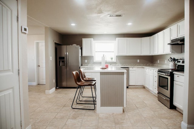 kitchen with a kitchen breakfast bar, white cabinetry, a center island, and stainless steel appliances