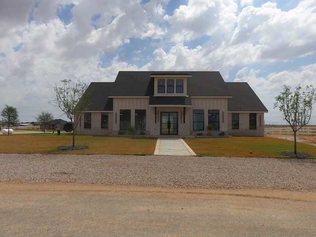 9811 E County Rd 108, Midland, TX 79706 - view of front of home with board and batten siding, a front yard, gravel driveway, brick siding, and roof with shingles