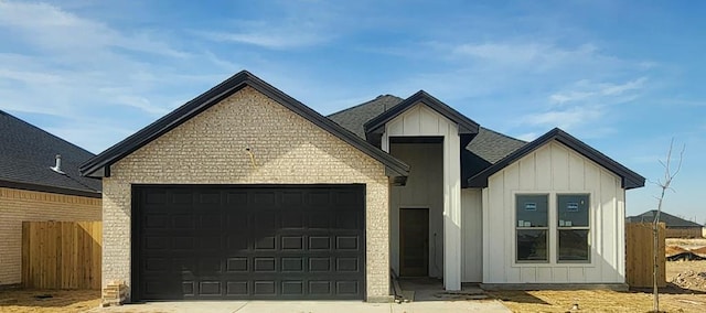 modern farmhouse style home with board and batten siding, fence, concrete driveway, roof with shingles, and an attached garage