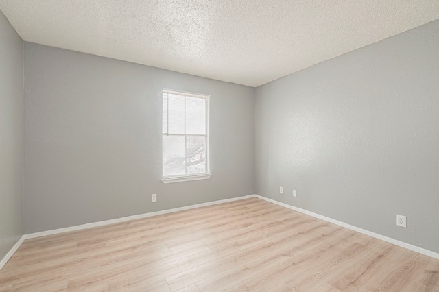 empty room featuring a textured ceiling and light hardwood / wood-style flooring