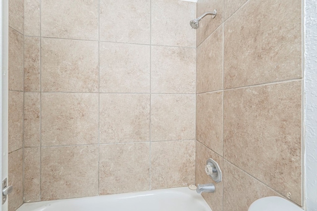 room details featuring tiled shower / bath combo and toilet