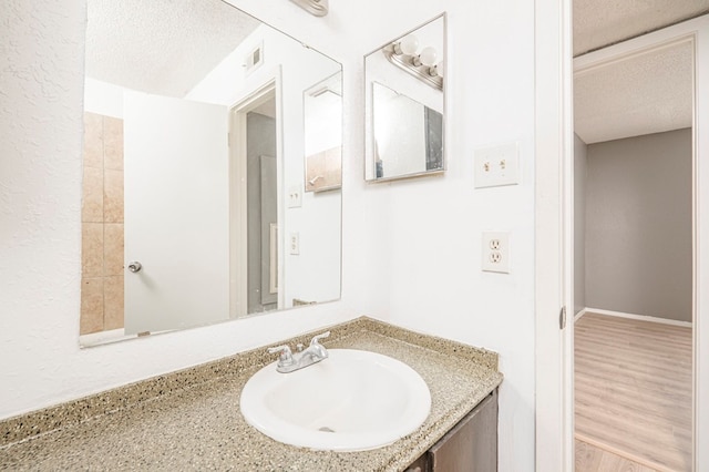 bathroom with vanity, hardwood / wood-style floors, and a textured ceiling