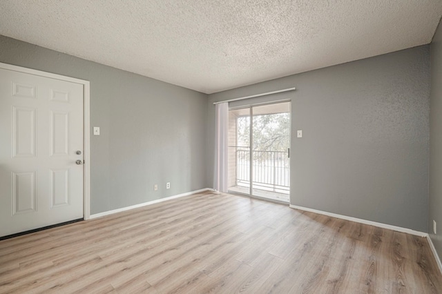 unfurnished room with a textured ceiling and light wood-type flooring