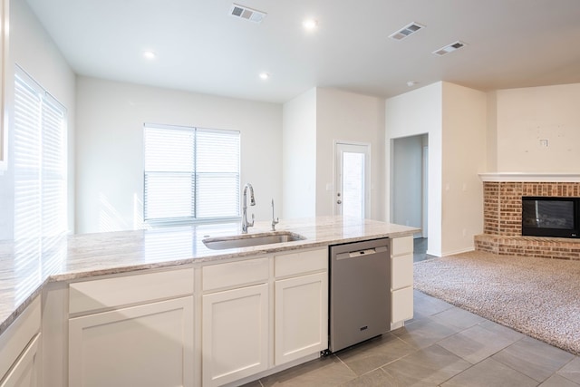 kitchen with sink, dishwasher, white cabinetry, light stone countertops, and light colored carpet