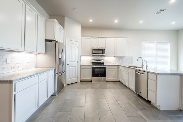 kitchen featuring light stone counters, sink, white cabinets, and appliances with stainless steel finishes