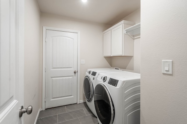 laundry area with cabinets, dark tile patterned floors, and washer and clothes dryer