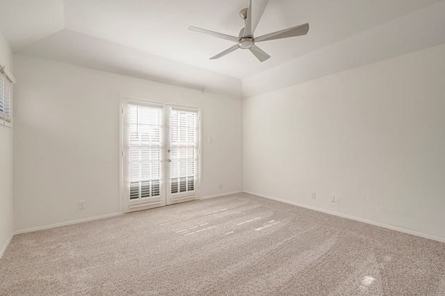 unfurnished room featuring a tray ceiling, light carpet, ceiling fan, and vaulted ceiling