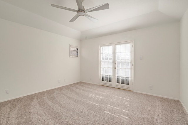 carpeted spare room featuring a tray ceiling, ceiling fan, french doors, and lofted ceiling