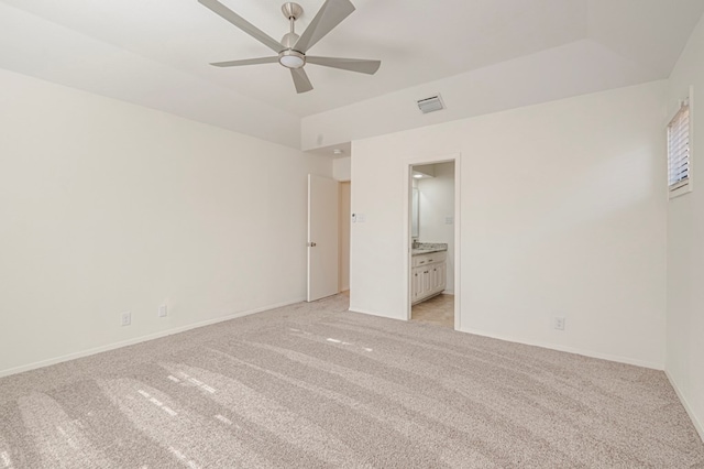 unfurnished bedroom featuring light colored carpet, ensuite bath, and ceiling fan