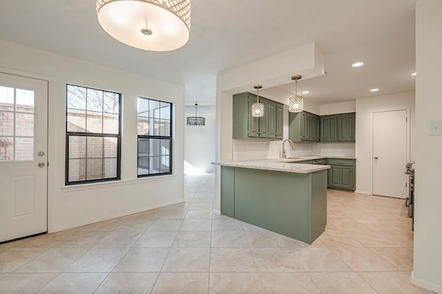 kitchen with light stone countertops, sink, kitchen peninsula, light tile patterned floors, and green cabinetry