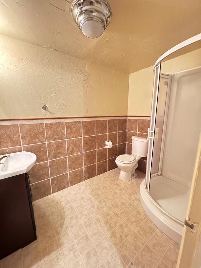 2100 42nd St, Snyder, TX 79549 - bathroom featuring vanity, toilet, a shower with door, and tile walls