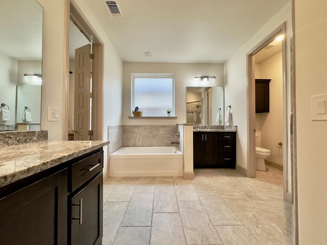 bathroom with vanity, toilet, and a tub to relax in