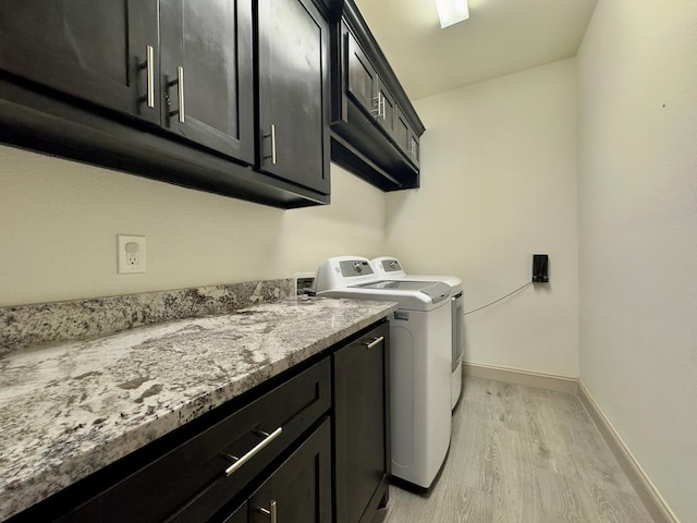 clothes washing area with separate washer and dryer, cabinets, and light hardwood / wood-style floors