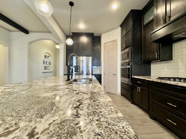 kitchen with hanging light fixtures, stainless steel appliances, light stone counters, light hardwood / wood-style flooring, and decorative backsplash