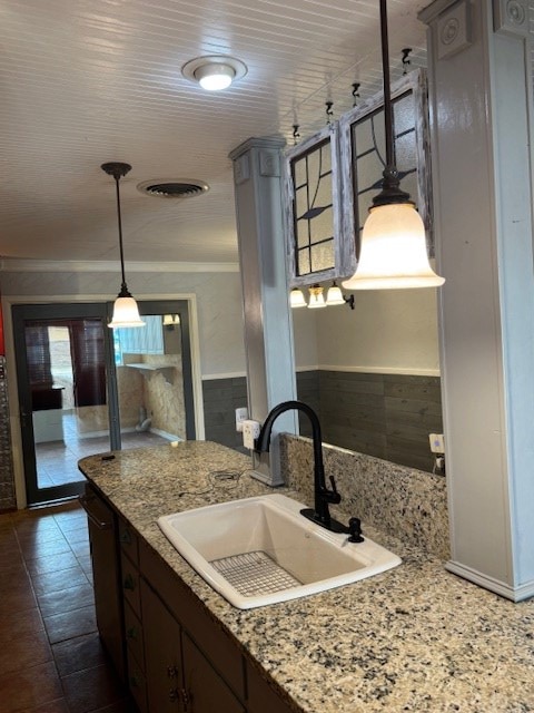 906 W 5th St, Fort Stockton, TX 79735 - kitchen with black dishwasher, pendant lighting, a wainscoted wall, light stone countertops, and dark brown cabinetry