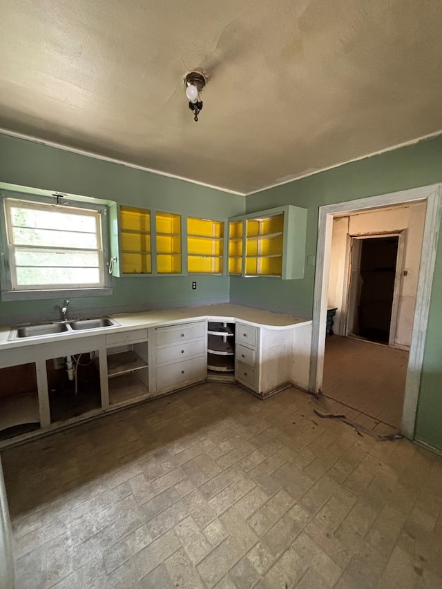 kitchen featuring brick patterned floor, built in study area, light countertops, and a sink