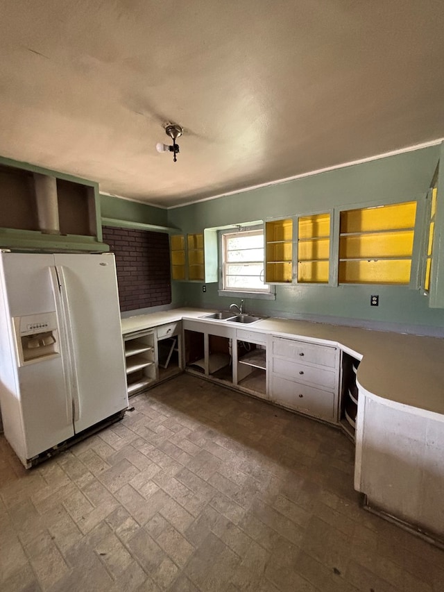 kitchen with open shelves, brick floor, light countertops, and white refrigerator with ice dispenser