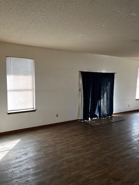 spare room featuring a textured ceiling and dark wood-type flooring