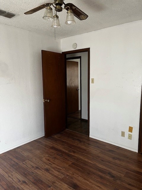 spare room with a textured ceiling, ceiling fan, and dark hardwood / wood-style floors