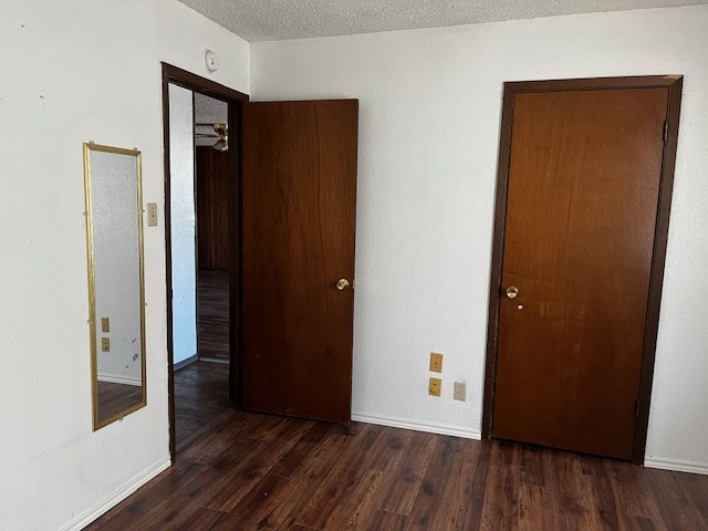 unfurnished bedroom with dark wood-type flooring and a textured ceiling