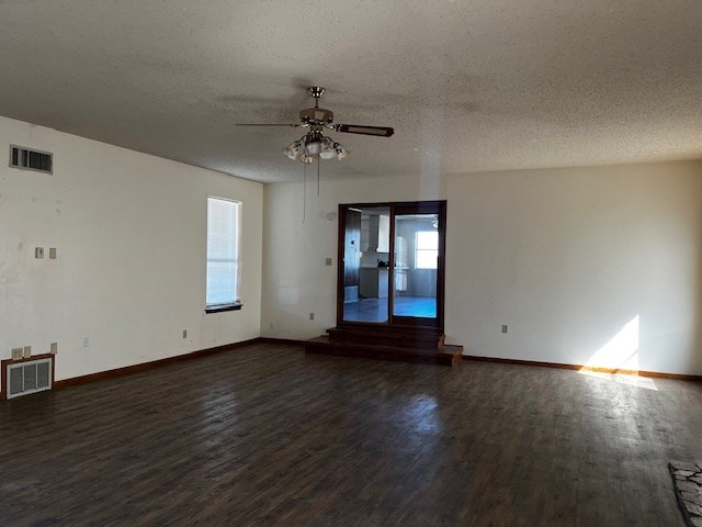 spare room with a textured ceiling, ceiling fan, and dark hardwood / wood-style flooring