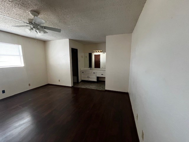 empty room with dark wood-type flooring, a textured ceiling, and ceiling fan