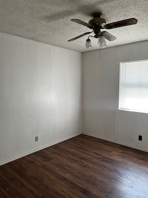 empty room with a textured ceiling, ceiling fan, and dark hardwood / wood-style floors