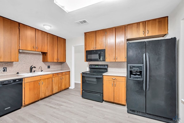 3404 W Michigan Ave, Midland, TX 79703 - kitchen with black appliances, a sink, light countertops, light wood-style floors, and backsplash