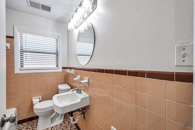 3404 W Michigan Ave, Midland, TX 79703 - bathroom featuring tile walls, wainscoting, toilet, and a sink