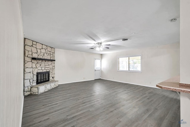 3404 W Michigan Ave, Midland, TX 79703 - unfurnished living room featuring a ceiling fan, dark wood-type flooring, a stone fireplace, and baseboards