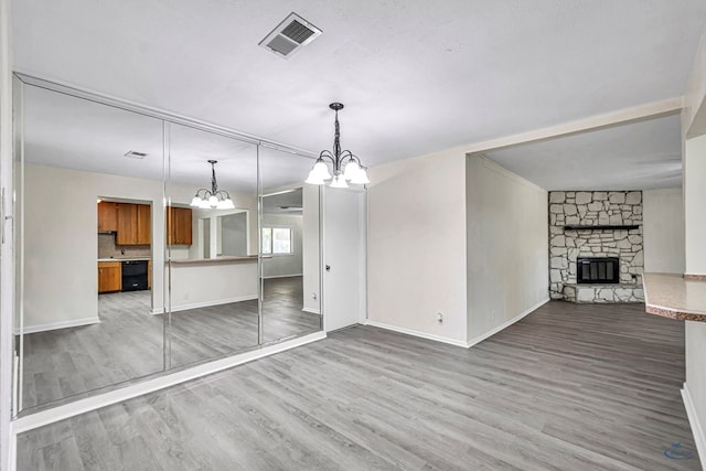 3404 W Michigan Ave, Midland, TX 79703 - unfurnished living room featuring a chandelier, wood finished floors, a stone fireplace, and baseboards