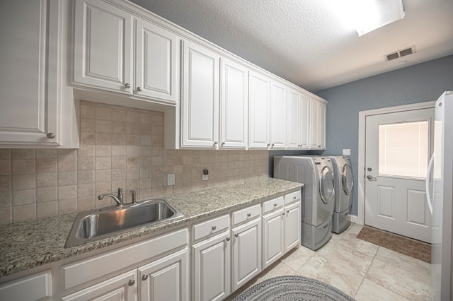 clothes washing area featuring cabinets, sink, independent washer and dryer, a textured ceiling, and light tile patterned flooring