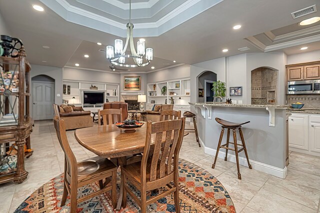 dining room featuring built in shelves, crown molding, a chandelier, and a tray ceiling