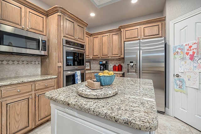 kitchen with decorative backsplash, appliances with stainless steel finishes, light stone countertops, crown molding, and a center island