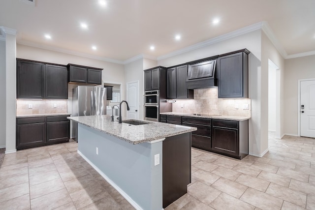 kitchen featuring sink, an island with sink, light stone countertops, and tasteful backsplash