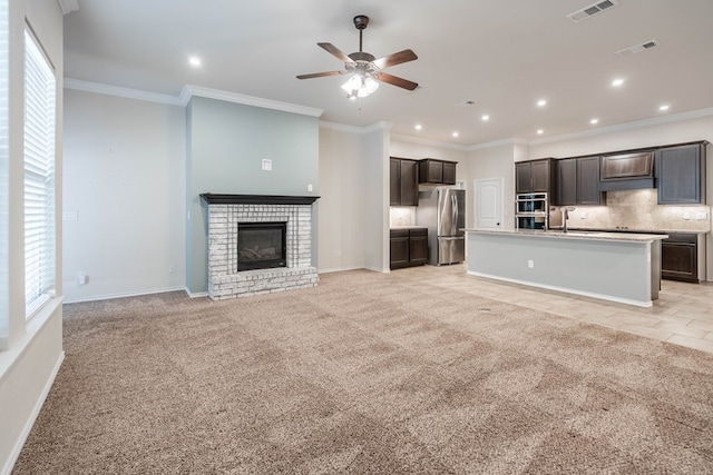 unfurnished living room with light colored carpet, sink, crown molding, and a fireplace