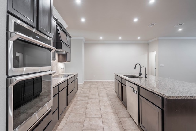 kitchen with sink, appliances with stainless steel finishes, ornamental molding, and a kitchen island with sink