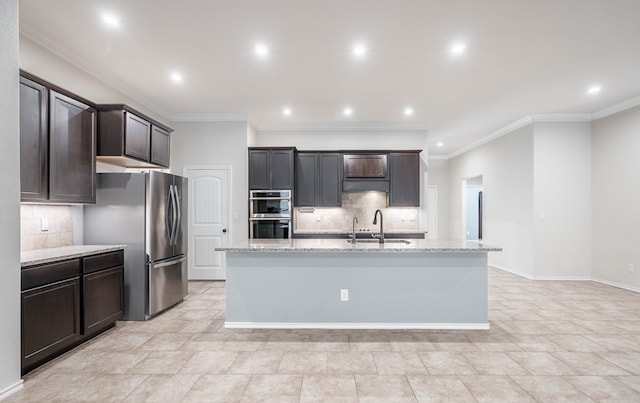 kitchen featuring sink, an island with sink, stainless steel appliances, and light stone counters