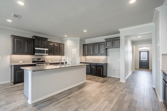 1212 Santa Clara, Midland, TX 79705 - kitchen with appliances with stainless steel finishes, backsplash, an island with sink, light wood-style floors, and recessed lighting