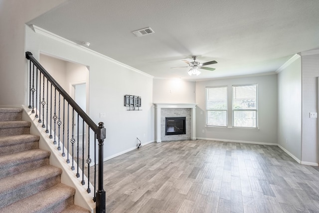 1212 Santa Clara, Midland, TX 79705 - unfurnished living room with a ceiling fan, crown molding, wood finished floors, a glass covered fireplace, and stairway