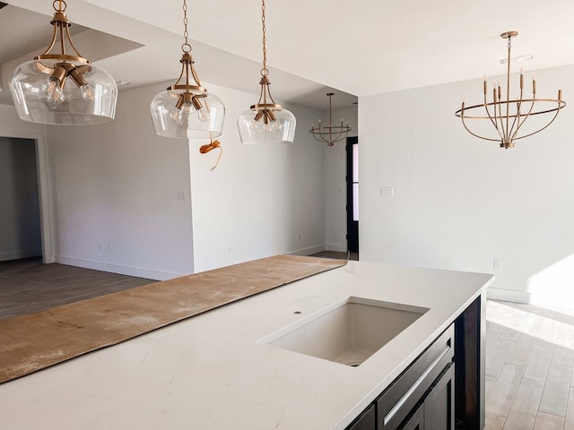 kitchen with a chandelier, sink, hanging light fixtures, and wood-type flooring