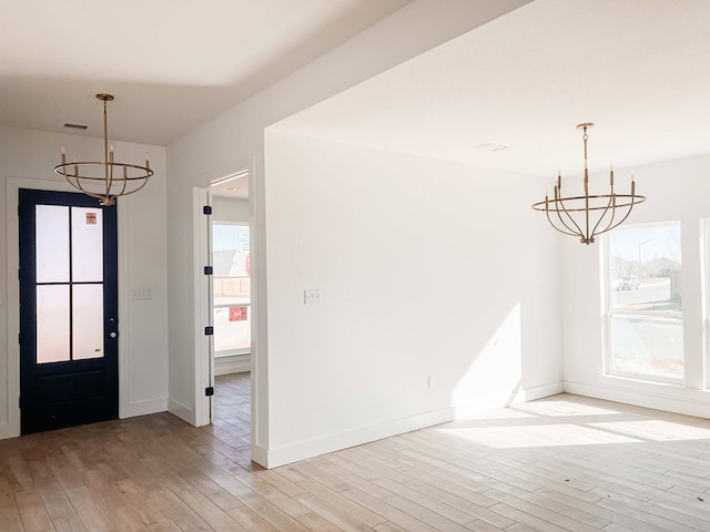 foyer featuring light hardwood / wood-style floors, a healthy amount of sunlight, and an inviting chandelier