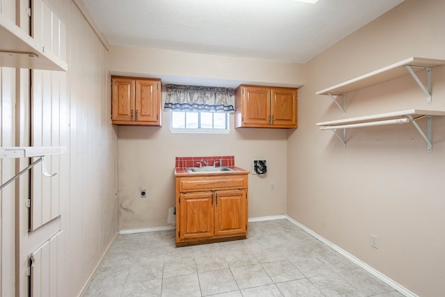 washroom with sink, electric dryer hookup, cabinets, a textured ceiling, and light tile patterned flooring