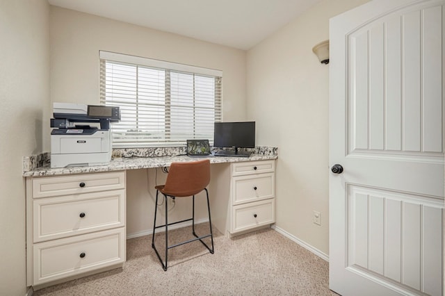 office space featuring built in study area, baseboards, and light carpet