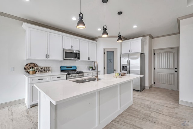 kitchen with appliances with stainless steel finishes, sink, white cabinets, hanging light fixtures, and a center island with sink