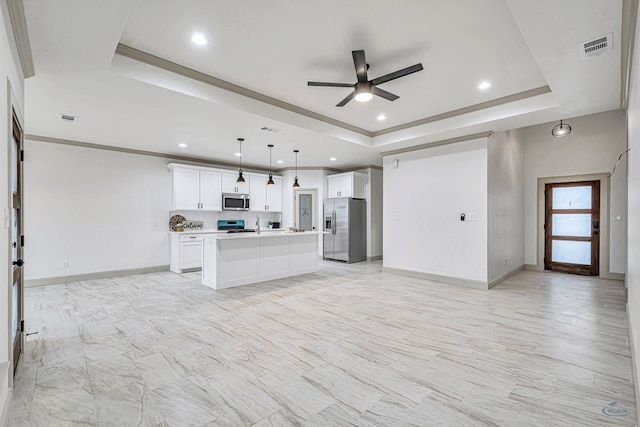 kitchen with stainless steel appliances, decorative light fixtures, a raised ceiling, and a kitchen island