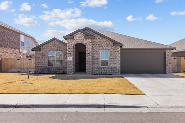 view of front of property featuring an attached garage, brick siding, fence, driveway, and a front lawn