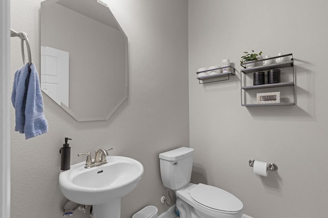 bathroom with baseboards, a sink, and toilet